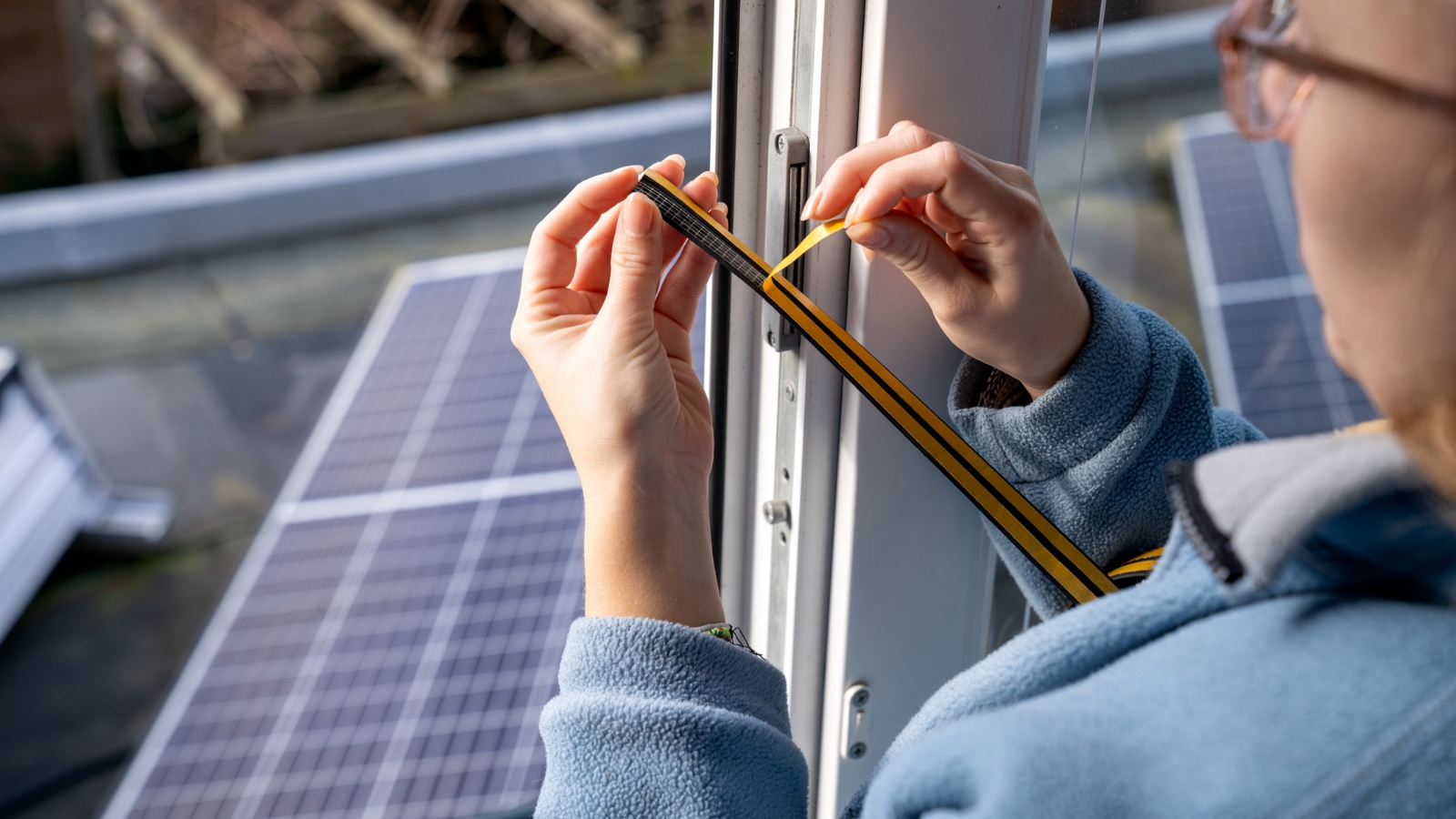 close-up of homeowner putting in weather strips on window