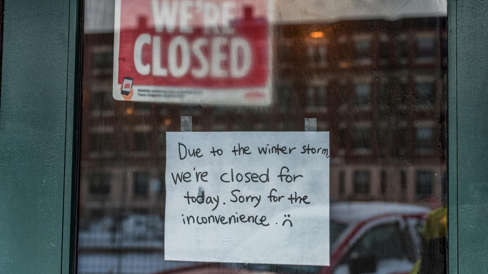 close-up of sign on shop window saying closed due to weather